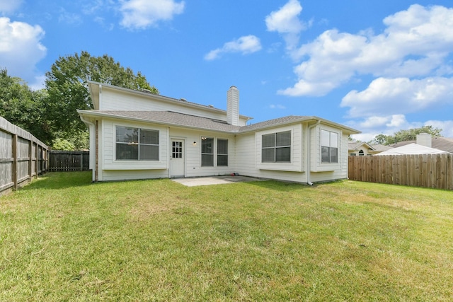 back of property with a patio area, a lawn, a chimney, and a fenced backyard