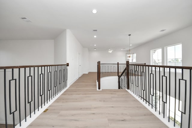 hallway featuring visible vents, an upstairs landing, a notable chandelier, light wood-style flooring, and recessed lighting