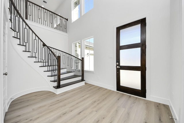 entryway with stairs, a high ceiling, wood finished floors, and baseboards