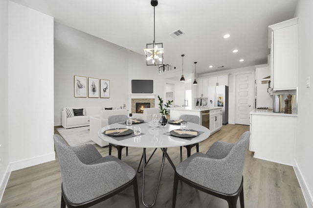 dining space featuring recessed lighting, visible vents, a stone fireplace, and light wood finished floors