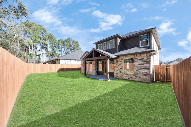 back of house featuring a yard, a fenced backyard, a shingled roof, a patio area, and brick siding