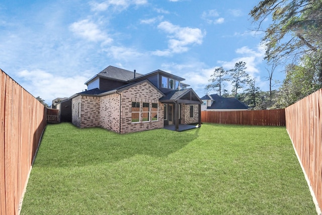 back of property with a yard, a fenced backyard, and brick siding