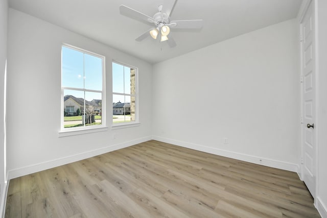 spare room with light wood finished floors, ceiling fan, and baseboards