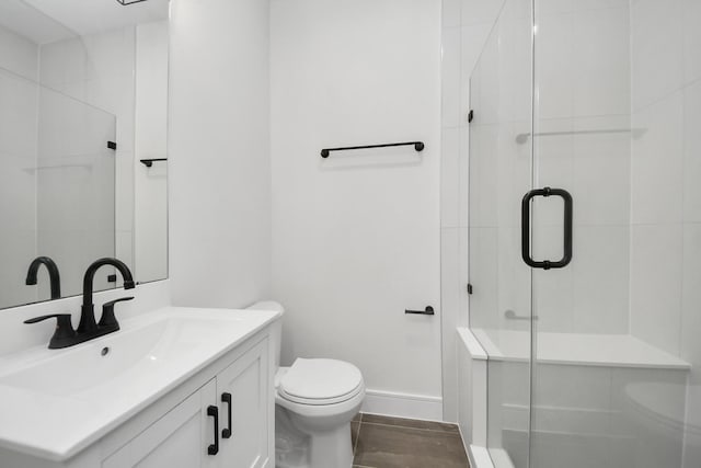 full bathroom featuring a shower stall, baseboards, toilet, wood finished floors, and vanity