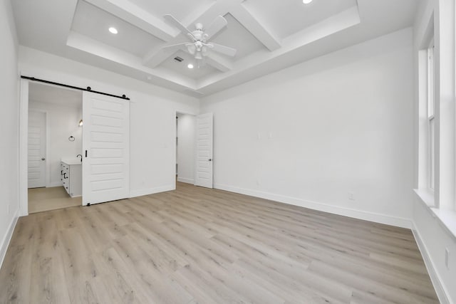 unfurnished bedroom with a barn door, light wood-style flooring, baseboards, and coffered ceiling