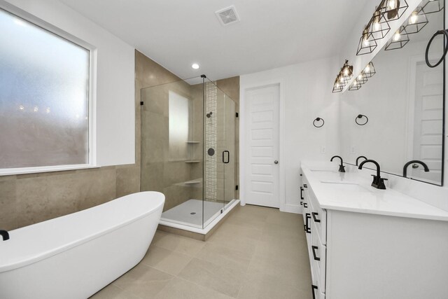 bathroom featuring visible vents, a shower stall, a freestanding bath, double vanity, and a sink