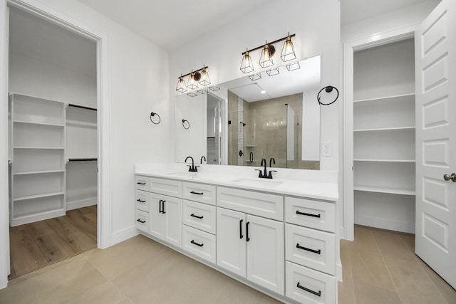 full bath featuring a shower stall, a spacious closet, double vanity, and a sink