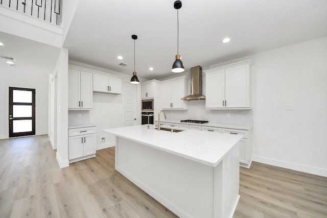 kitchen with oven, a sink, stainless steel microwave, wall chimney range hood, and tasteful backsplash