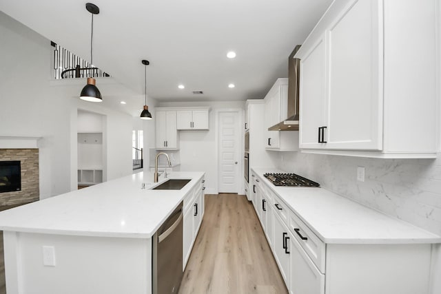 kitchen with tasteful backsplash, appliances with stainless steel finishes, wall chimney exhaust hood, and a sink