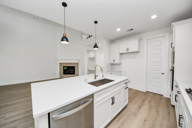 kitchen featuring visible vents, a sink, white cabinets, stainless steel dishwasher, and light wood-type flooring