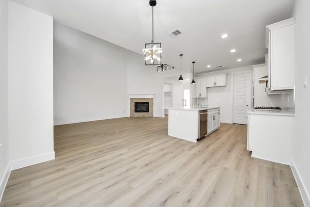 kitchen with light wood finished floors, visible vents, open floor plan, white cabinetry, and stainless steel dishwasher