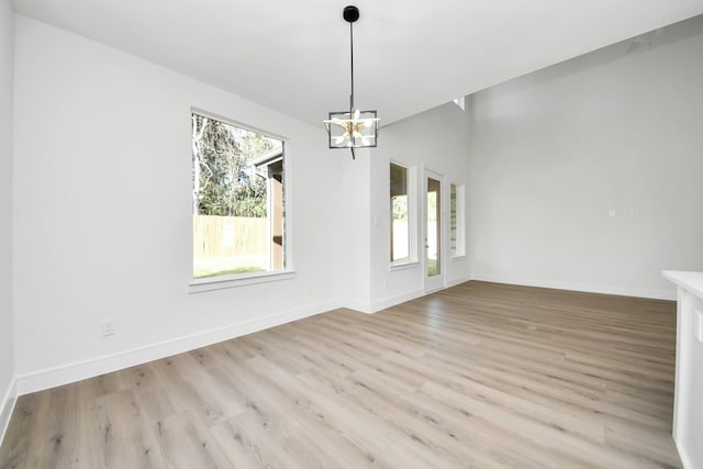 interior space with an inviting chandelier, light wood-style flooring, and baseboards