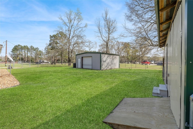 view of yard featuring a detached garage, an outdoor structure, and fence