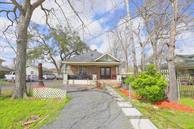 bungalow featuring a porch, brick siding, and a fenced front yard