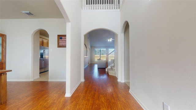 hallway with visible vents, baseboards, and wood finished floors