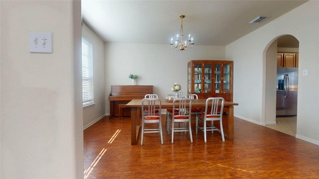 dining room with wood finished floors, arched walkways, visible vents, and a chandelier