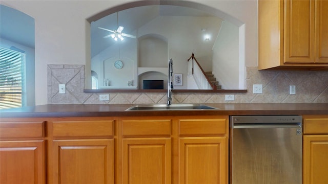 kitchen featuring dark countertops, decorative backsplash, a sink, and stainless steel dishwasher