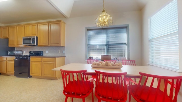 kitchen with stainless steel microwave, backsplash, a chandelier, decorative light fixtures, and gas stove