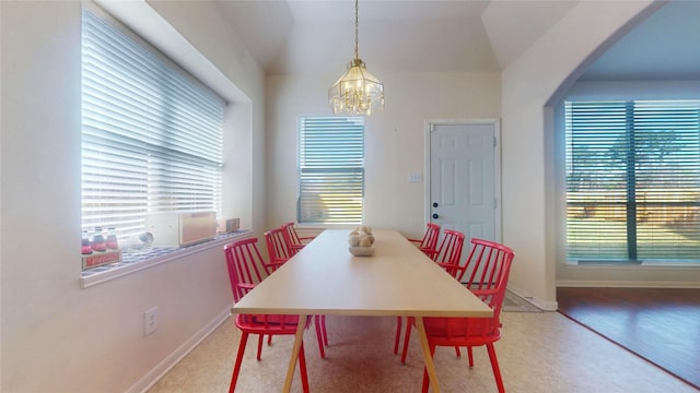 dining room featuring a chandelier, a healthy amount of sunlight, arched walkways, and baseboards