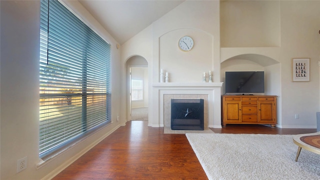 unfurnished living room featuring a fireplace, dark wood-style floors, baseboards, and high vaulted ceiling