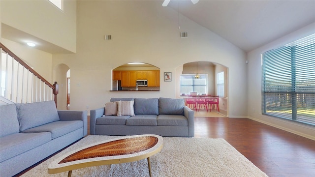 living area featuring wood finished floors, baseboards, visible vents, arched walkways, and ceiling fan