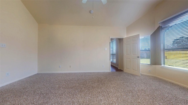 carpeted empty room featuring lofted ceiling, a ceiling fan, and baseboards