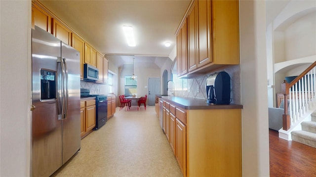 kitchen featuring arched walkways, a sink, appliances with stainless steel finishes, tasteful backsplash, and light wood-type flooring