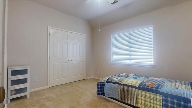 bedroom featuring visible vents, baseboards, lofted ceiling, light carpet, and a closet