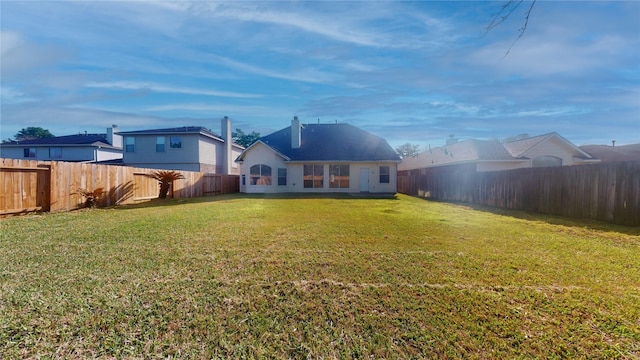 rear view of house with a lawn and a fenced backyard