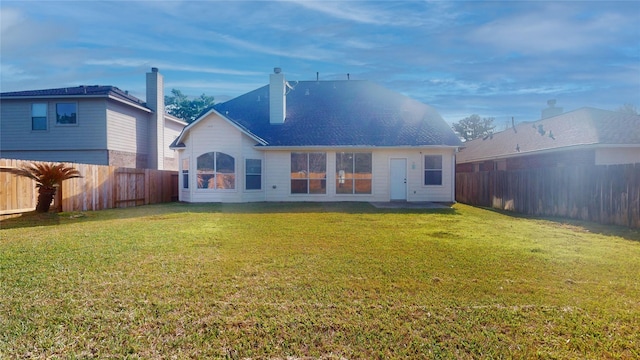 back of property featuring a yard and a fenced backyard