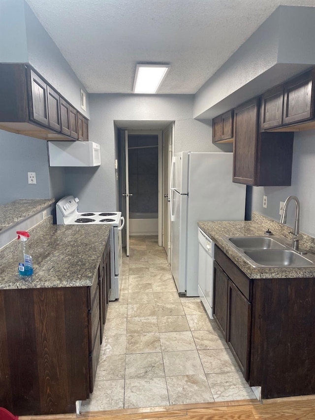 kitchen featuring white appliances, dark brown cabinets, exhaust hood, and a sink