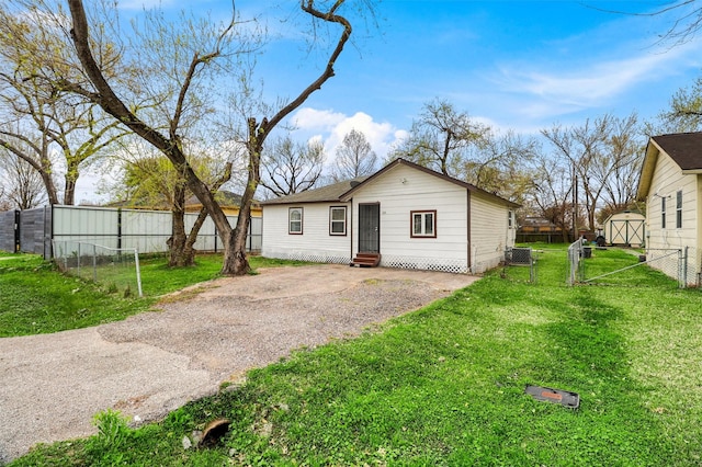 view of front of house with an outbuilding, fence, a front lawn, and entry steps