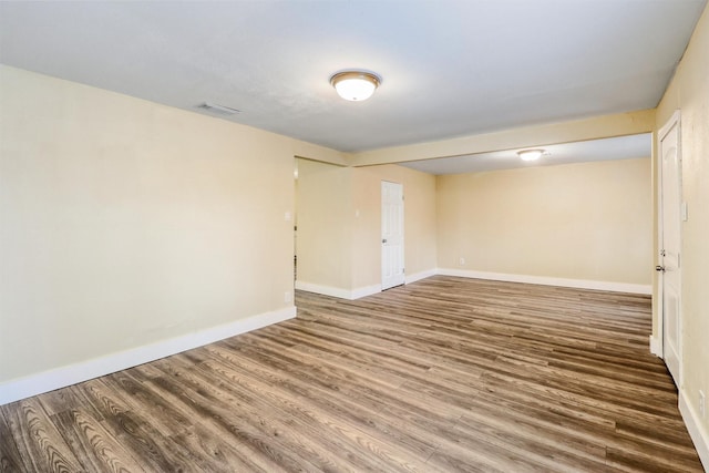 empty room with visible vents, baseboards, and wood finished floors