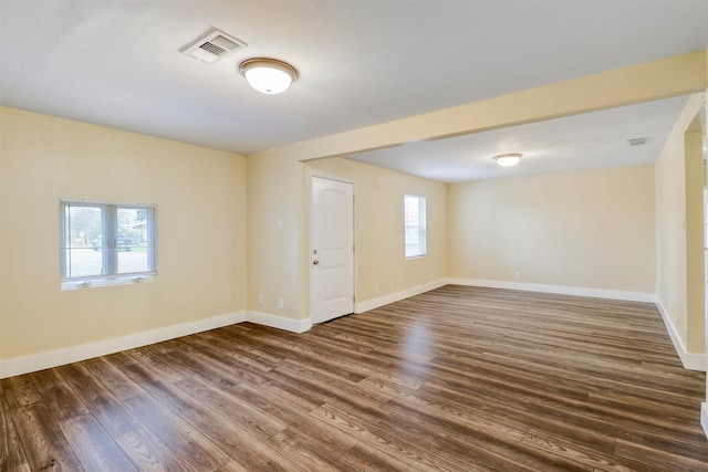 empty room with baseboards, visible vents, and dark wood-style flooring