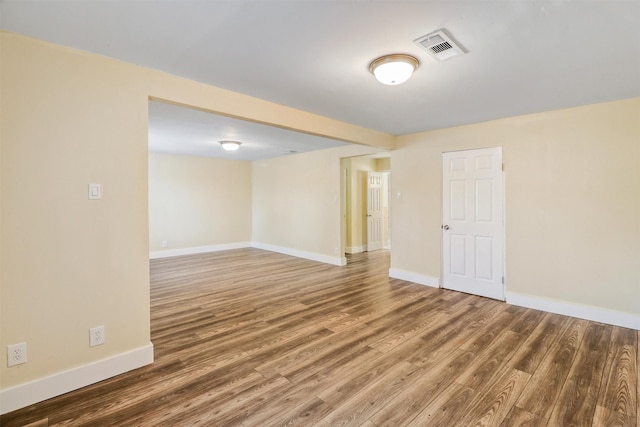 spare room with wood finished floors, visible vents, and baseboards