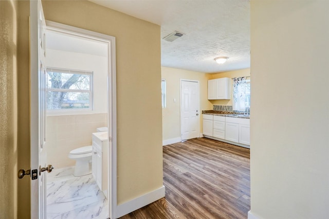 bathroom with vanity, visible vents, a textured ceiling, tile walls, and toilet