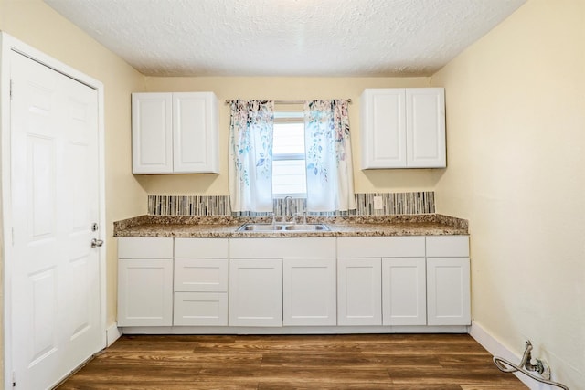 kitchen with dark wood-type flooring, white cabinets, and a sink