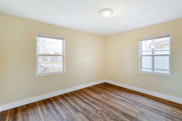 spare room with baseboards, a healthy amount of sunlight, and wood finished floors