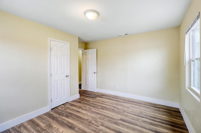 spare room featuring visible vents, baseboards, and wood finished floors