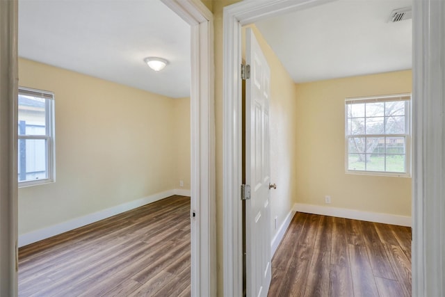 interior space with a healthy amount of sunlight, dark wood-style flooring, and baseboards