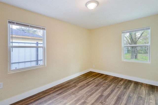 unfurnished room featuring baseboards and dark wood finished floors