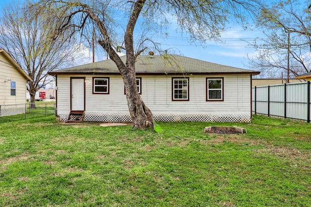 back of house with a lawn, entry steps, roof with shingles, and fence