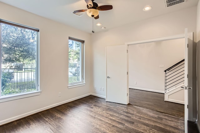 empty room featuring visible vents, baseboards, ceiling fan, stairway, and wood finished floors