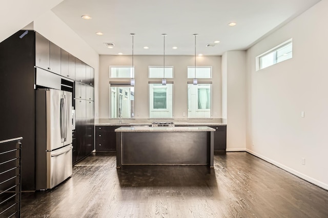 kitchen featuring recessed lighting, dark wood-style flooring, freestanding refrigerator, and a kitchen island