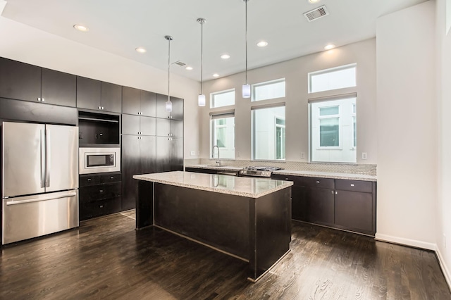 kitchen featuring visible vents, a kitchen island, dark wood-style flooring, stainless steel appliances, and a sink