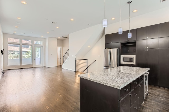 kitchen featuring a kitchen island, dark wood-style flooring, stainless steel appliances, decorative light fixtures, and open floor plan