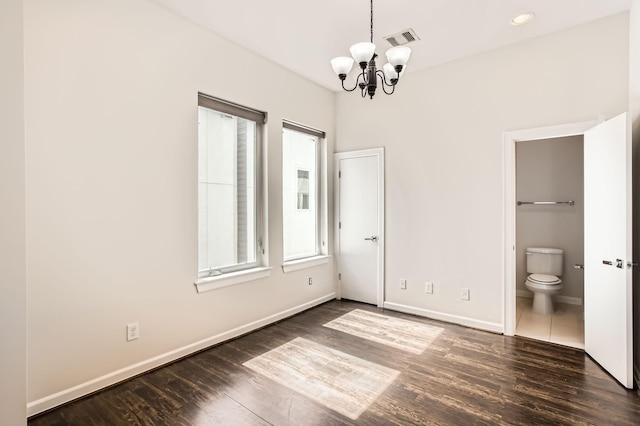 unfurnished bedroom with visible vents, dark wood-style floors, connected bathroom, baseboards, and a chandelier