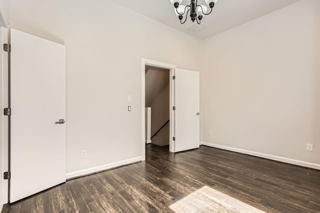 unfurnished bedroom with baseboards, an inviting chandelier, and wood finished floors