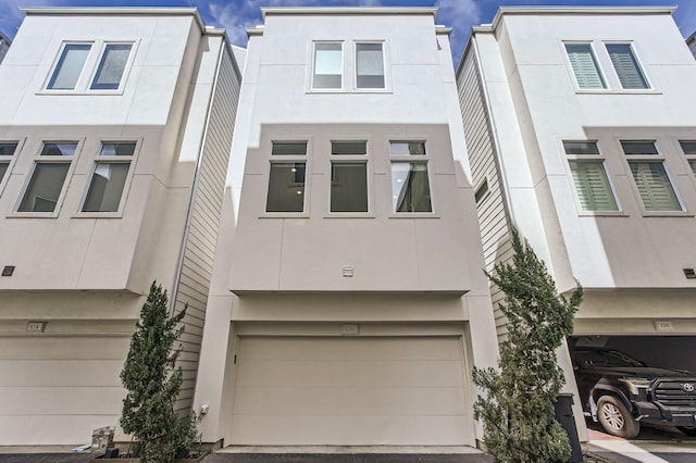 multi unit property with stucco siding and a garage