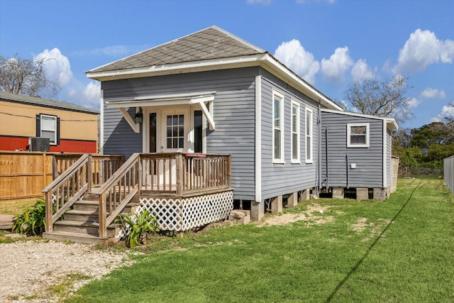 rear view of house with fence and a lawn